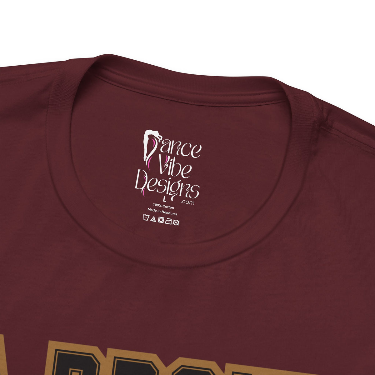 Close-up of a maroon crewneck t-shirt's inner neck label printed with the brand Dance Vibe Designs logo above the care instructions.