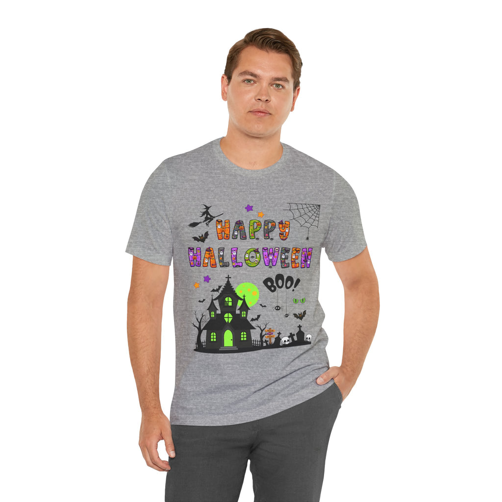 A man wearing a heather grey t-shirt with a colorful Happy Halloween text and haunted house design.