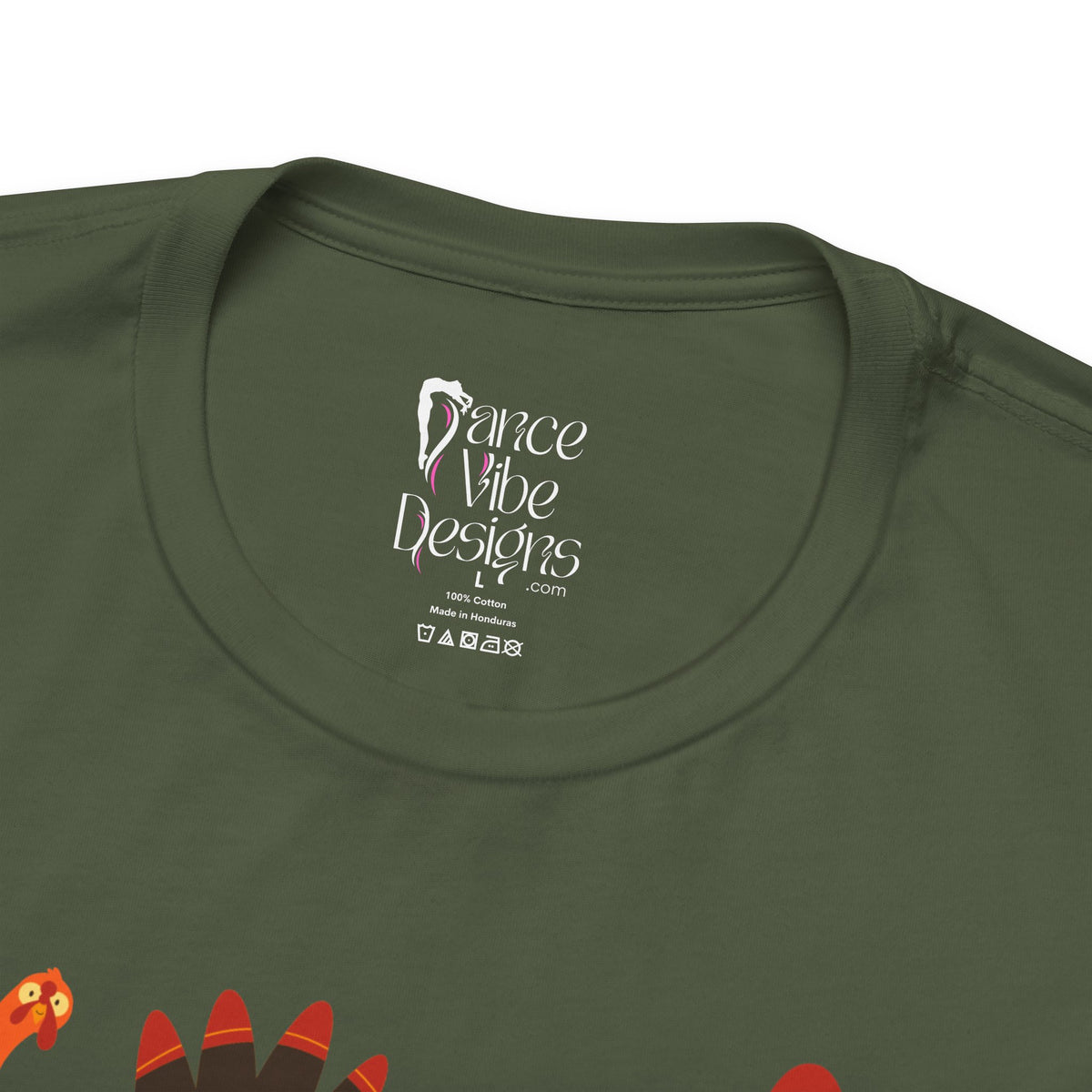 Close-up of a military green t-shirt showing the inner neck label with Dance Vibe Designs LLC printed in white, alongside care instructions.
