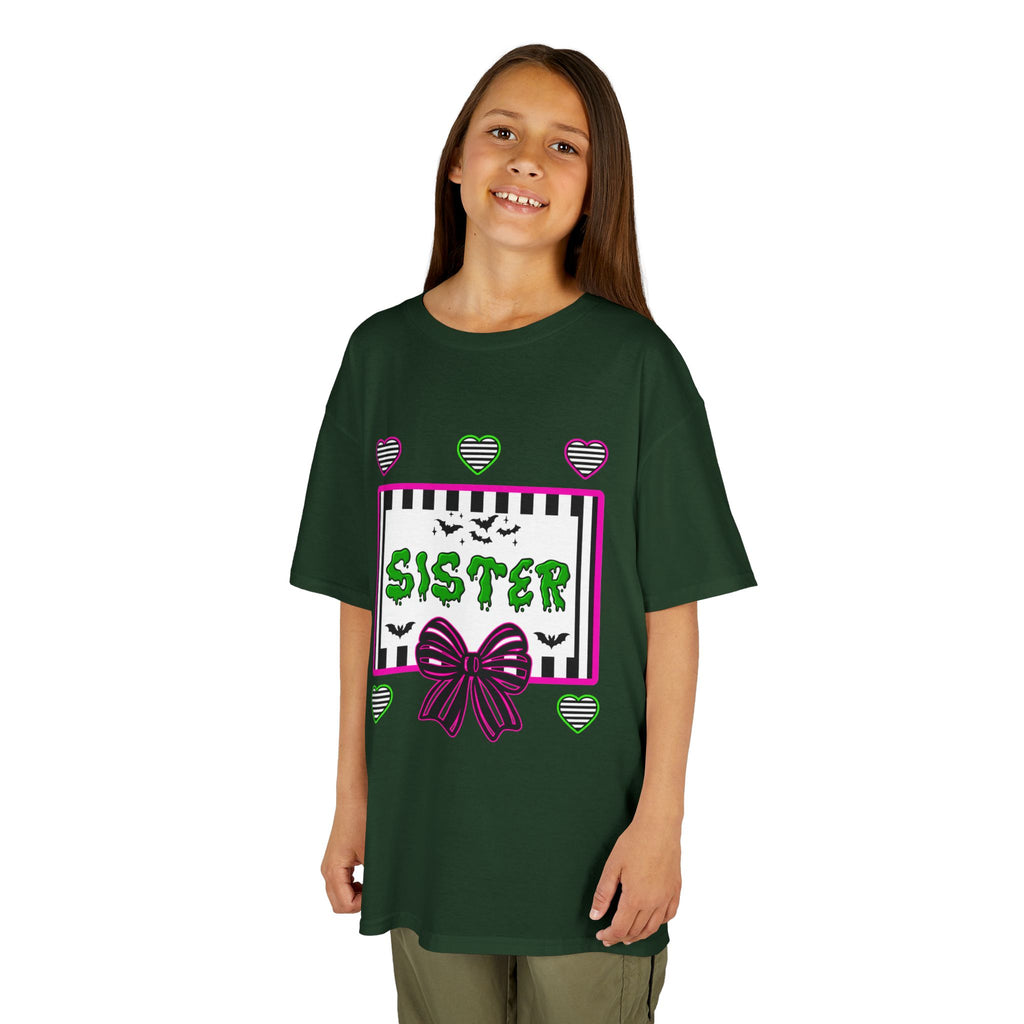 A young girl wearing a green t-shirt featuring a colorful Beetlejuice inspired Halloween-themed graphic with the word SISTER on the front. 