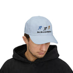 Man wearing a light blue baseball cap featuring embroidered running figures in blue, black, and tan above the text Meet Me at the Finish Line.