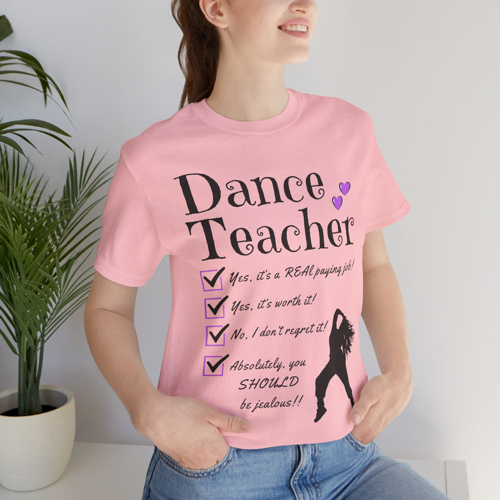 Woman wearing a pink short-sleeve graphic t-shirt featuring the text Dance Teacher with a jazz, hip hop dancer silhouette.