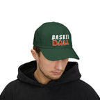 Man wearing a spruce baseball cap featuring BASKET BALL embroidered on the front, with BASKET in white and BALL in orange. 