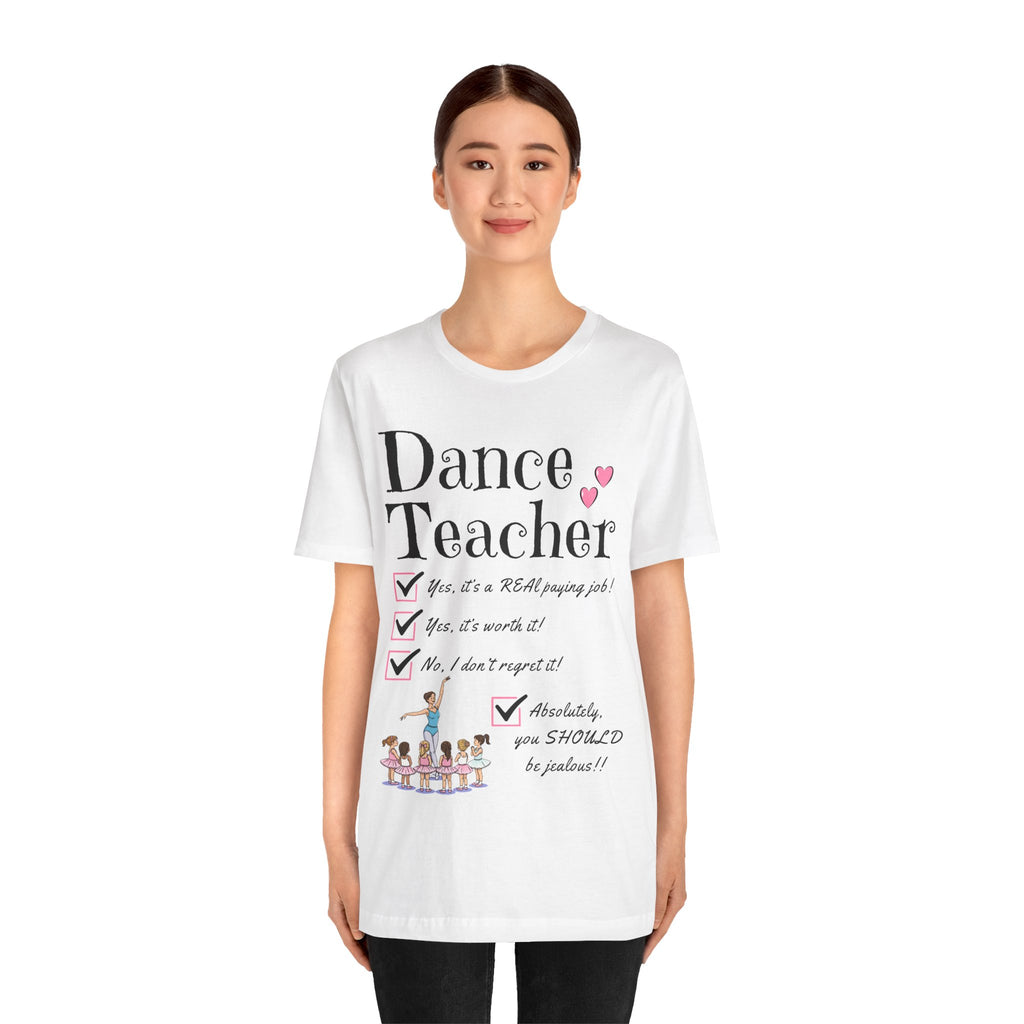 A young woman wearing a white short-sleeve crewneck t-shirt featuring a text that reads Dance Teacher and a ballet class graphic.