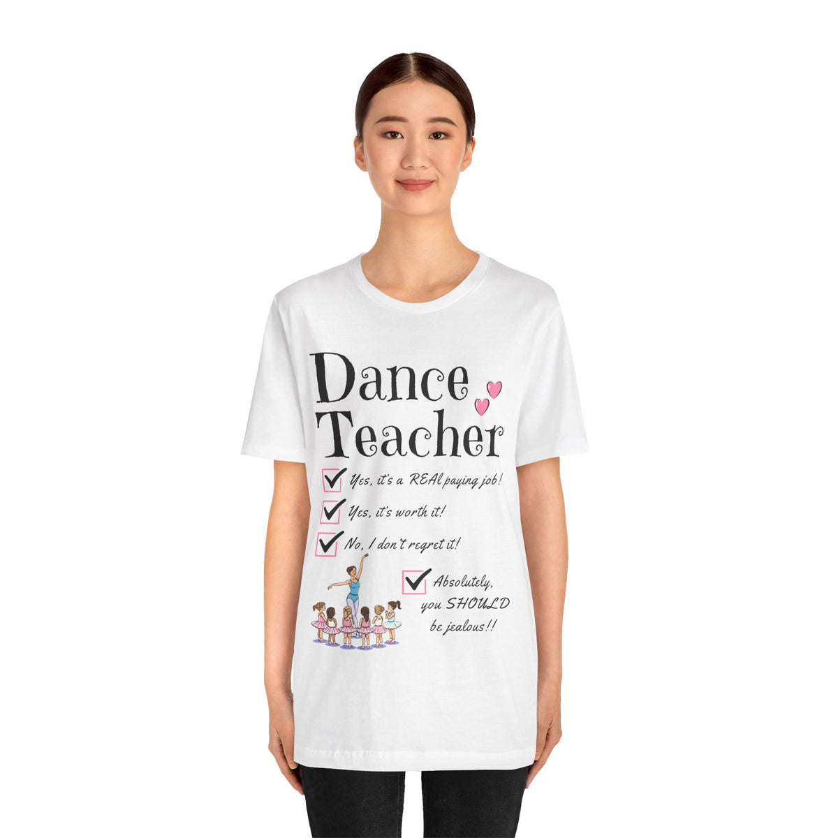 A young woman wearing a white short-sleeve crewneck t-shirt featuring a text that reads Dance Teacher and a ballet class graphic.