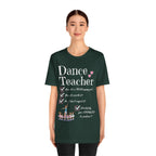 A young woman wearing a forest green short-sleeve crewneck t-shirt featuring a text that reads Dance Teacher and a ballet class graphic.