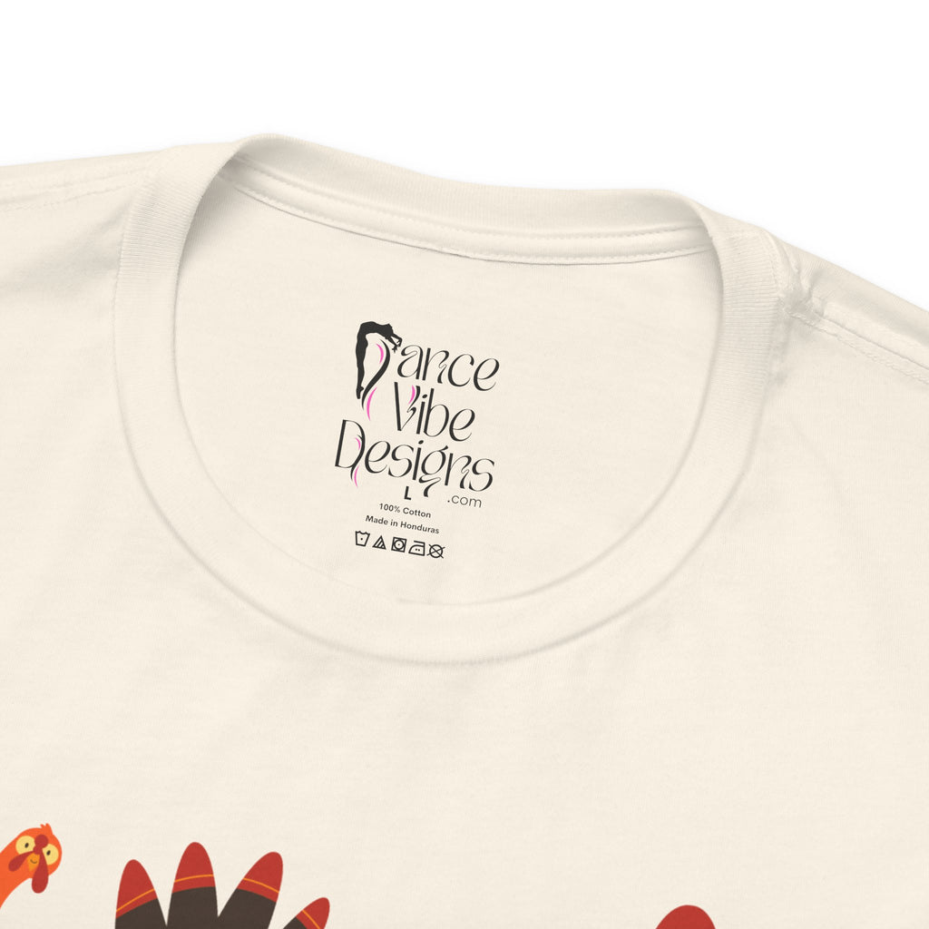 Close-up of a natural t-shirt showing the inner neck label with Dance Vibe Designs LLC printed in black, alongside care instructions.