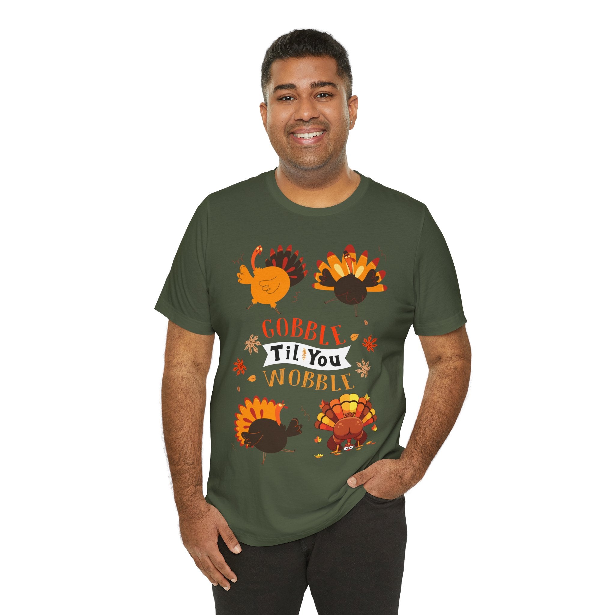 A man wearing a military green short-sleeve t-shirt with a colorful Thanksgiving graphic featuring cartoon turkeys and the text GOBBLE TIL YOU WOBBLE.