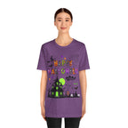 A woman wearing a purple t-shirt with a colorful Happy Halloween text and haunted house design.