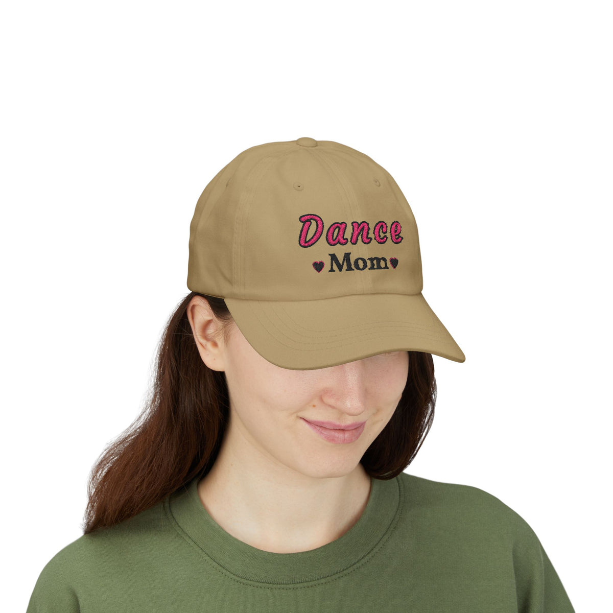 A woman wearing a khaki baseball cap featuring the embroidered text Dance Mom on the front. 