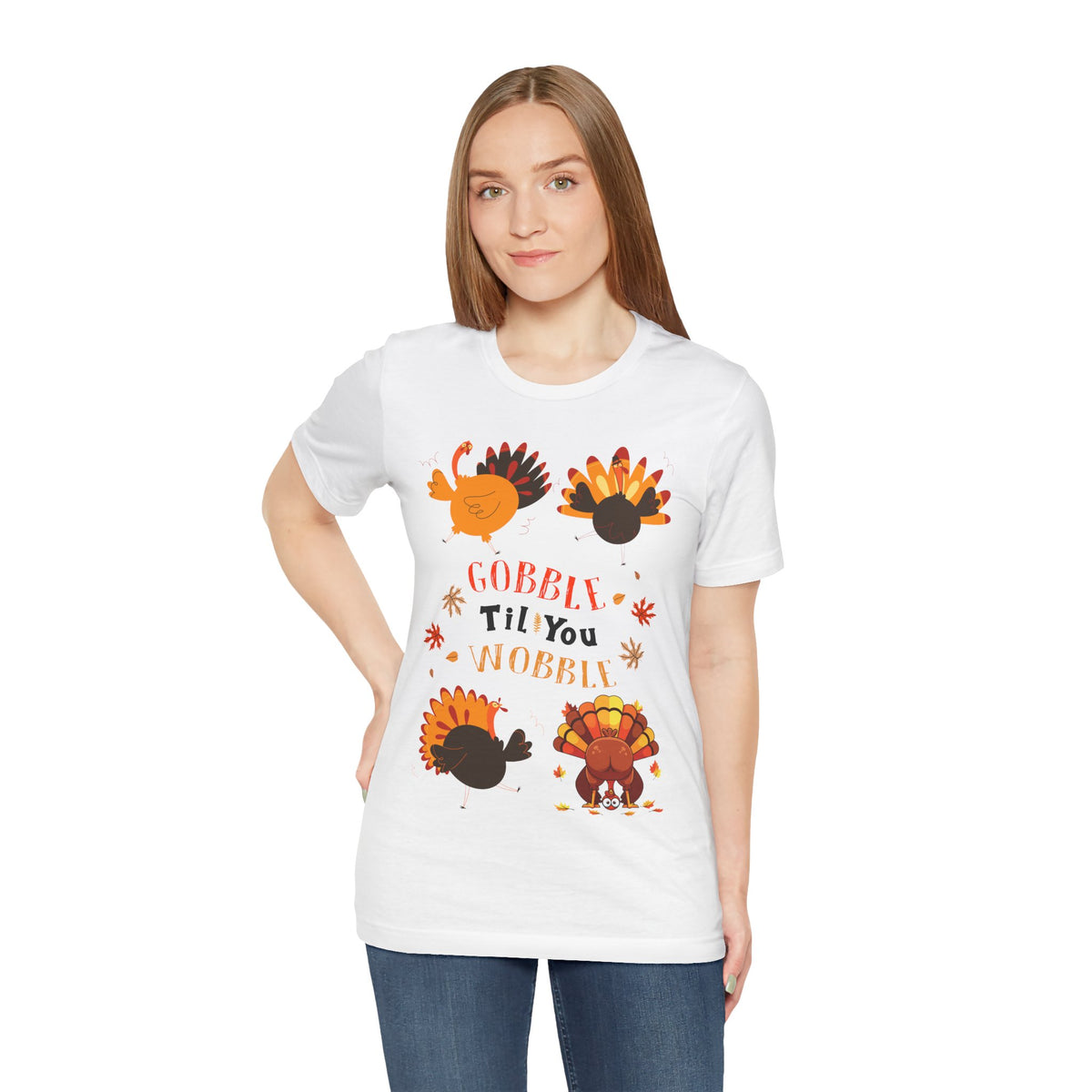 A woman wearing a white short-sleeve t-shirt with a colorful Thanksgiving graphic featuring cartoon turkeys and the text GOBBLE TIL YOU WOBBLE.