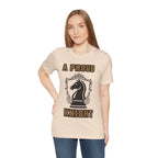 Woman wearing a soft cream graphic T-shirt with a black chess knight design and the words A PROUD KNIGHT on the front.
