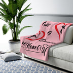 Pink blanket with Just a Dancer at Heart design draped over a sofa in a living room