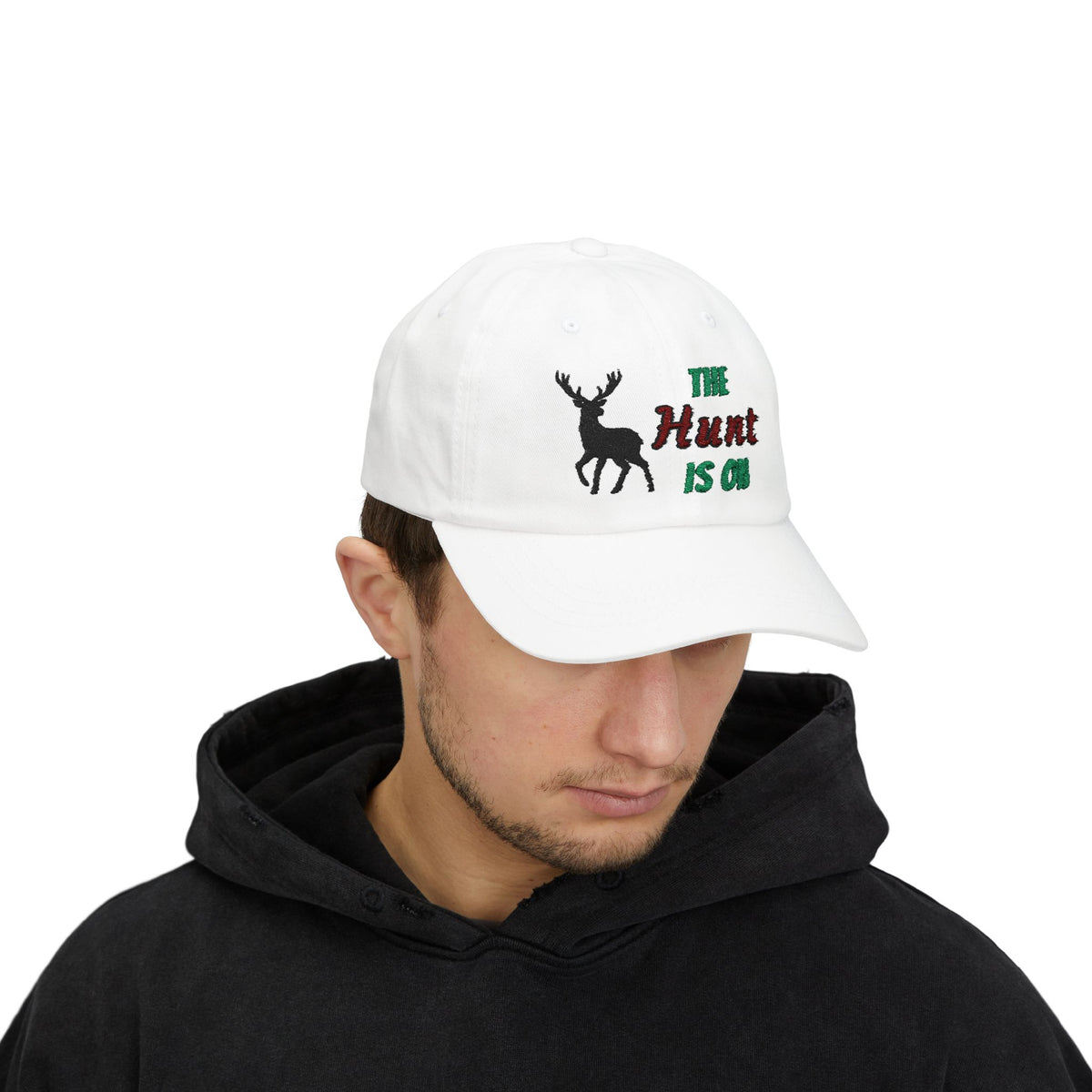 Man wearing a white cap with an embroidered deer silhouette and The Hunt Is On text.