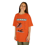 Young girl wearing a youth Gildan 5000B heavy cotton t-shirt in tennessee orange with a Swimming text and graphic
