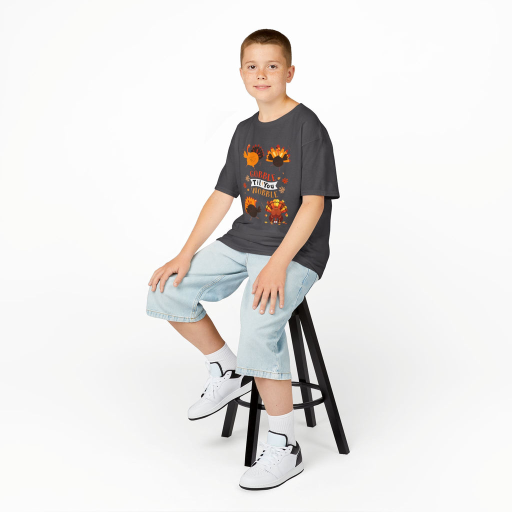 Young boy wearing a charcoal short-sleeve t-shirt with a colorful graphic of cartoon turkeys and the phrase GOBBLE TIL YOU WOBBLE on the front.