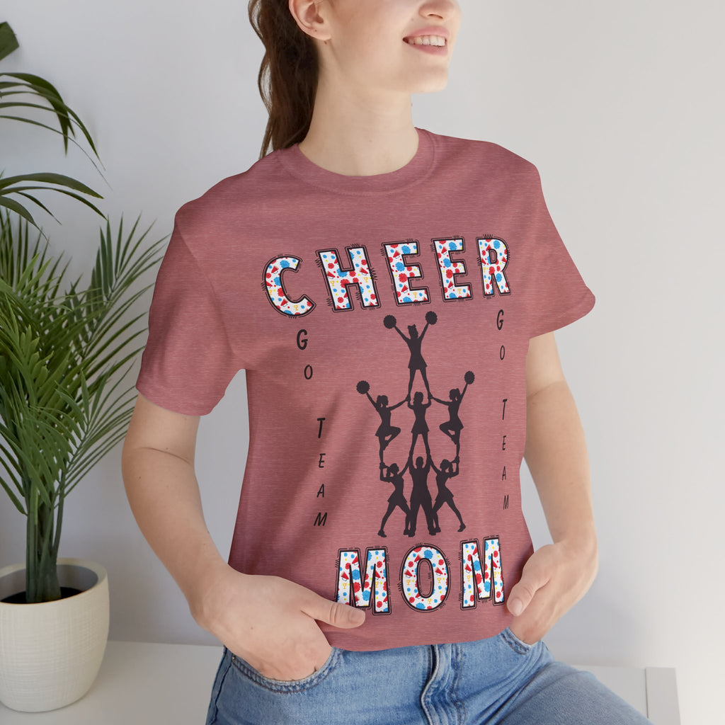 A woman wearing a heather mauve graphic t-shirt with CHEER GO TEAM MOM text and graphic on the front.