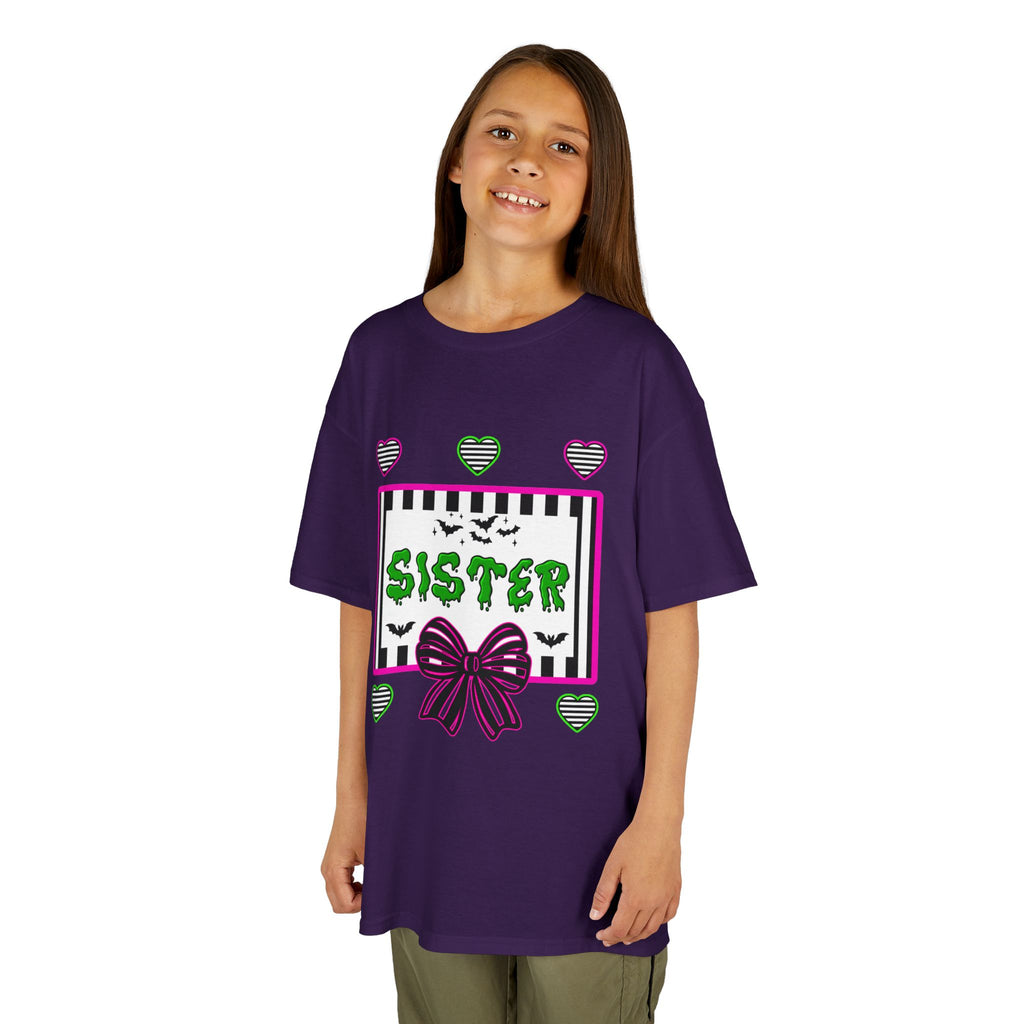 A young girl wearing a purple t-shirt featuring a colorful Beetlejuice inspired Halloween-themed graphic with the word SISTER on the front. 