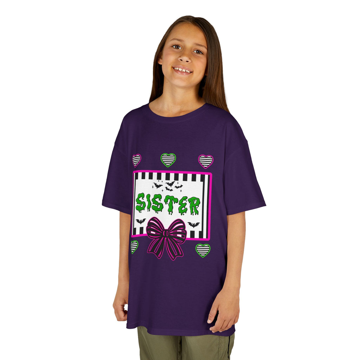 A young girl wearing a purple t-shirt featuring a colorful Beetlejuice inspired Halloween-themed graphic with the word SISTER on the front. 