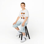 Young boy wearing a white short-sleeve t-shirt with a colorful graphic of cartoon turkeys and the phrase GOBBLE TIL YOU WOBBLE on the front.