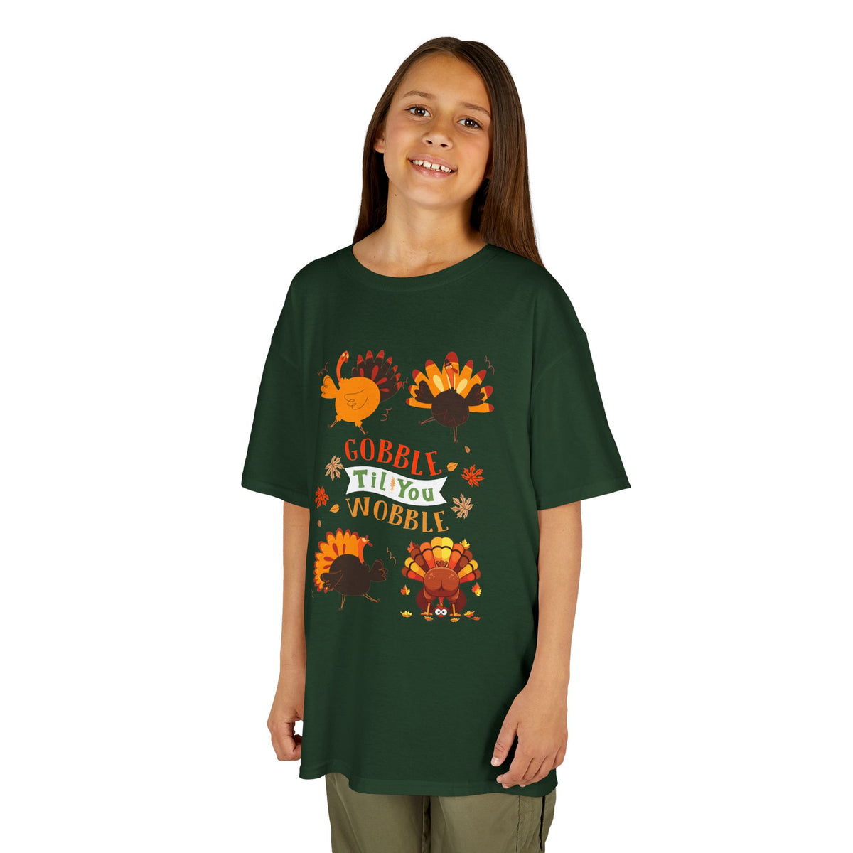 Young girl wearing a forest green short-sleeve t-shirt with a colorful graphic of cartoon turkeys and the phrase GOBBLE TIL YOU WOBBLE on the front.