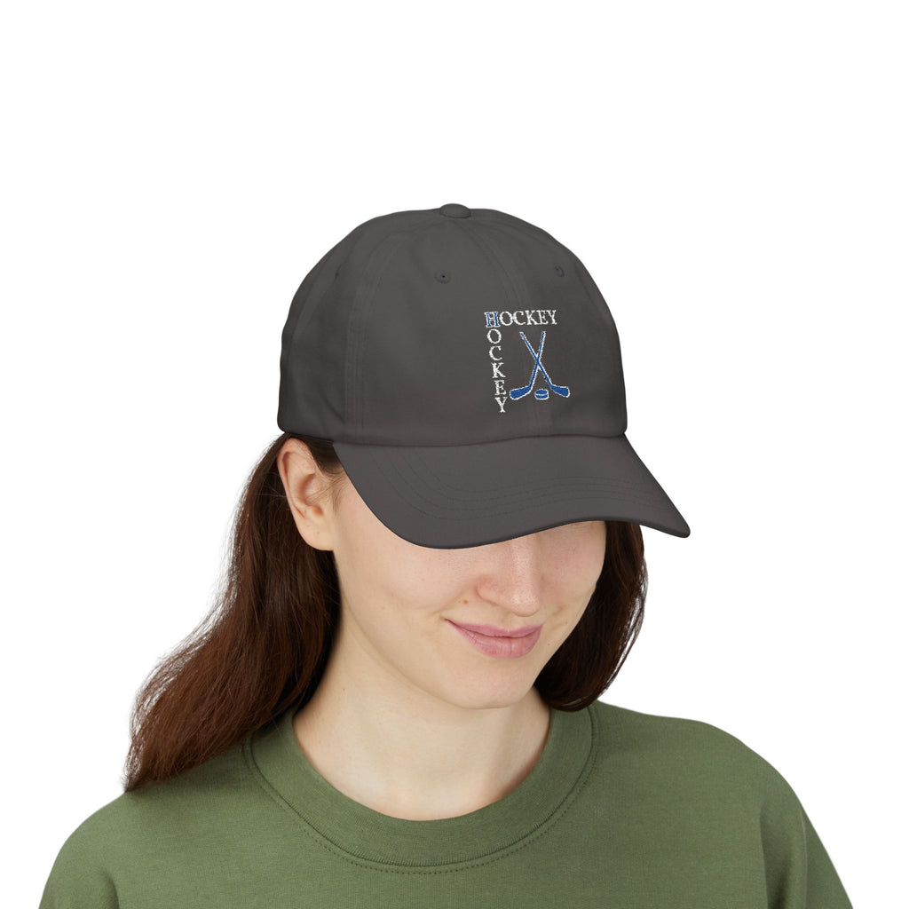 Woman wearing a dark grey cap with an embroidered Hockey text and logo.