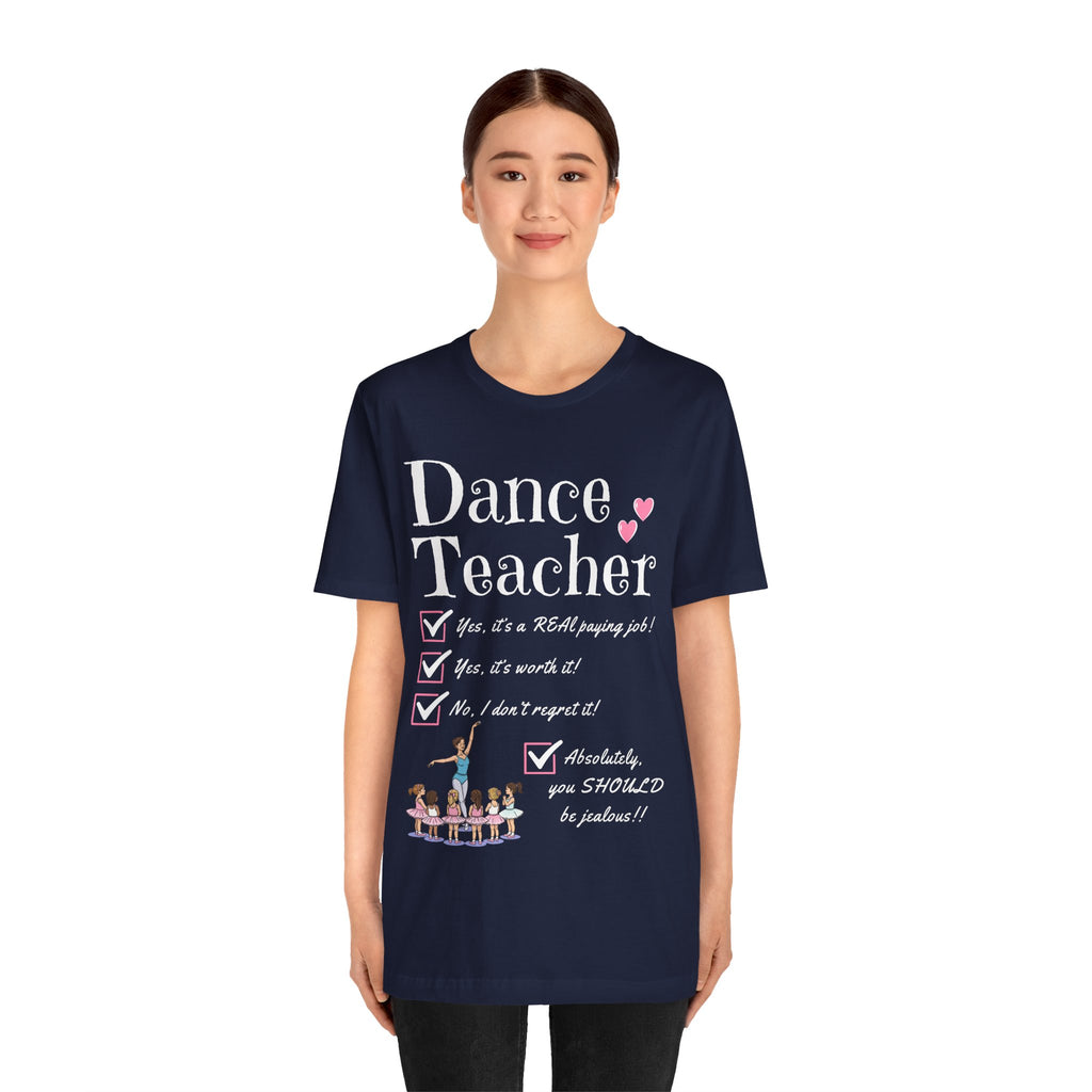 A young woman wearing a navy short-sleeve crewneck t-shirt featuring a text that reads Dance Teacher and a ballet class graphic.