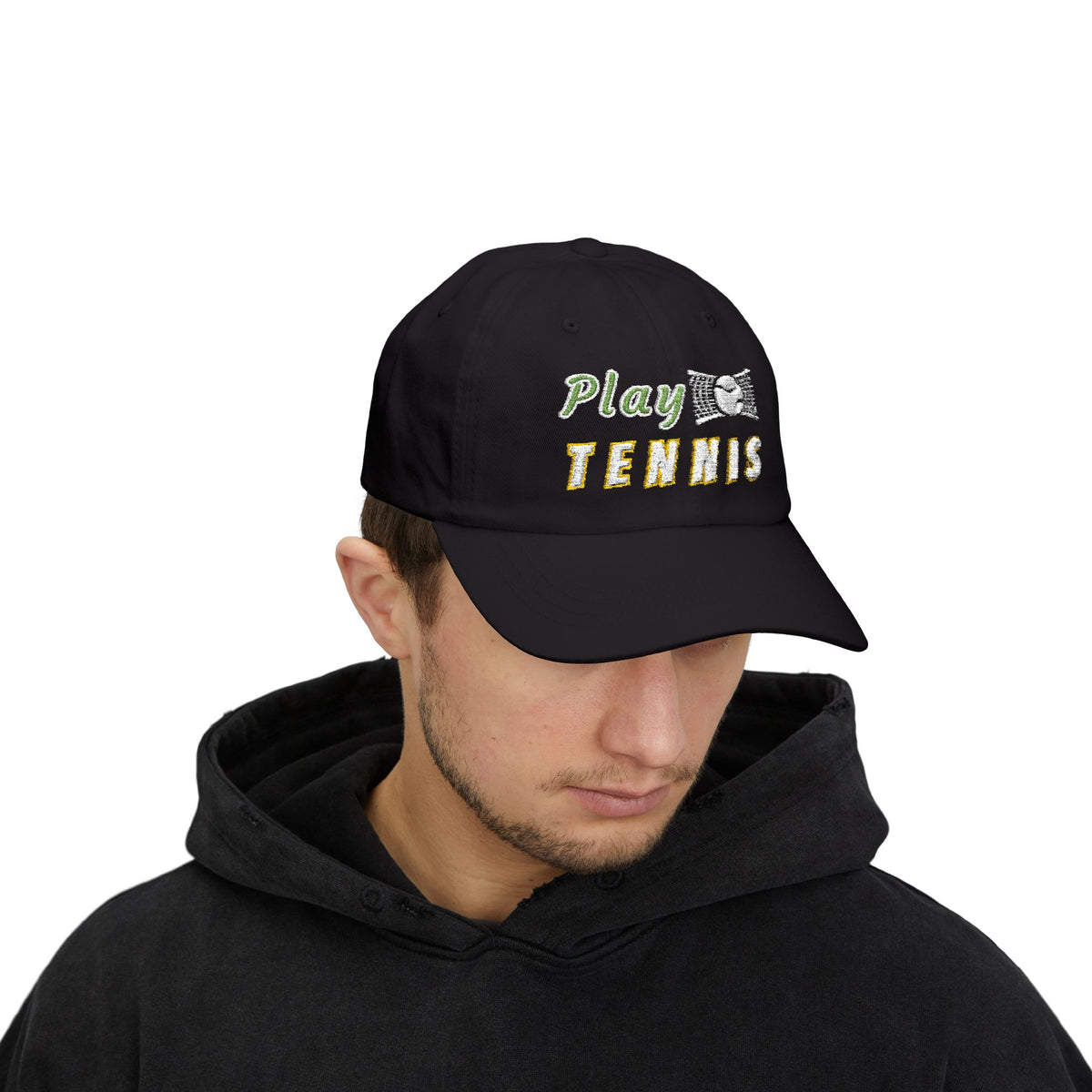 Man wearing a black baseball cap featuring the embroidered text Play TENNIS on the front.