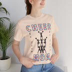 A woman wearing a soft cream graphic t-shirt with CHEER GO TEAM MOM text and graphic on the front.