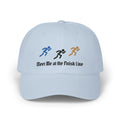 A light blue baseball cap featuring embroidered running figures in blue, black, and tan above the text Meet Me at the Finish Line.