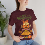 A woman wearing a maroon short-sleeve t-shirt with a Happy Thanksgiving graphic featuring a ballerina scarecrow design.