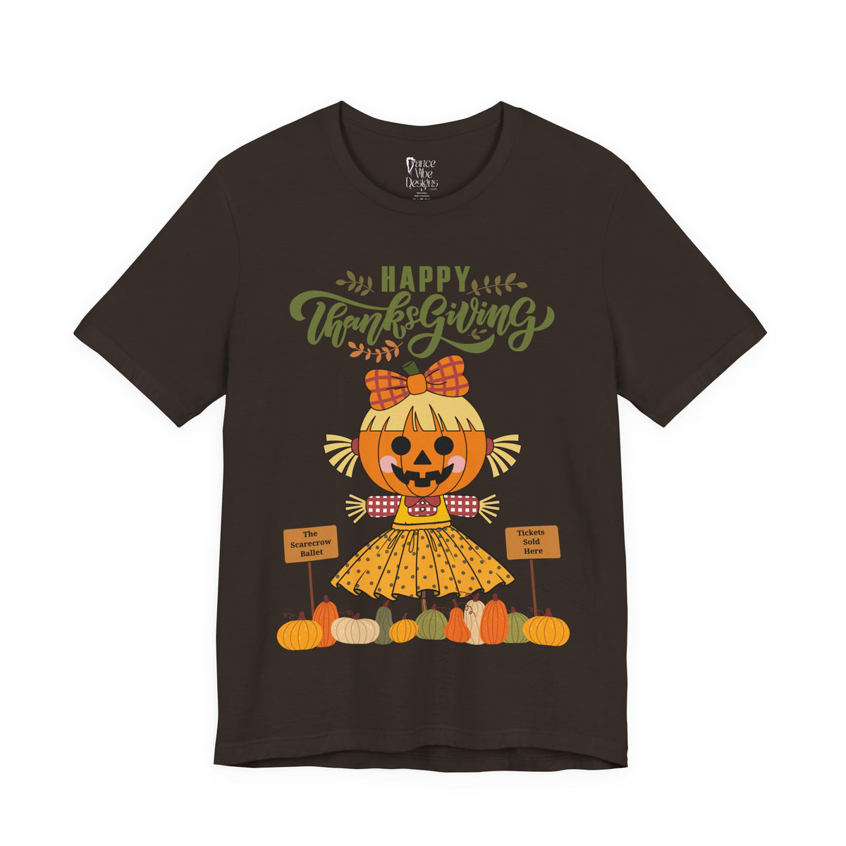 A brown short-sleeve t-shirt with a Happy Thanksgiving graphic featuring a ballerina scarecrow design.