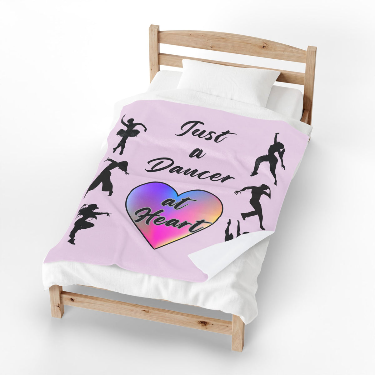 Pink velveteen plush throw blanket with dancer silhouettes a rainbow heart and Just a Dancer at Heart text covering a bed
