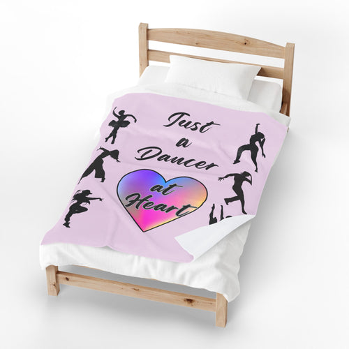 Pink velveteen plush throw blanket with dancer silhouettes a rainbow heart and Just a Dancer at Heart text covering a bed