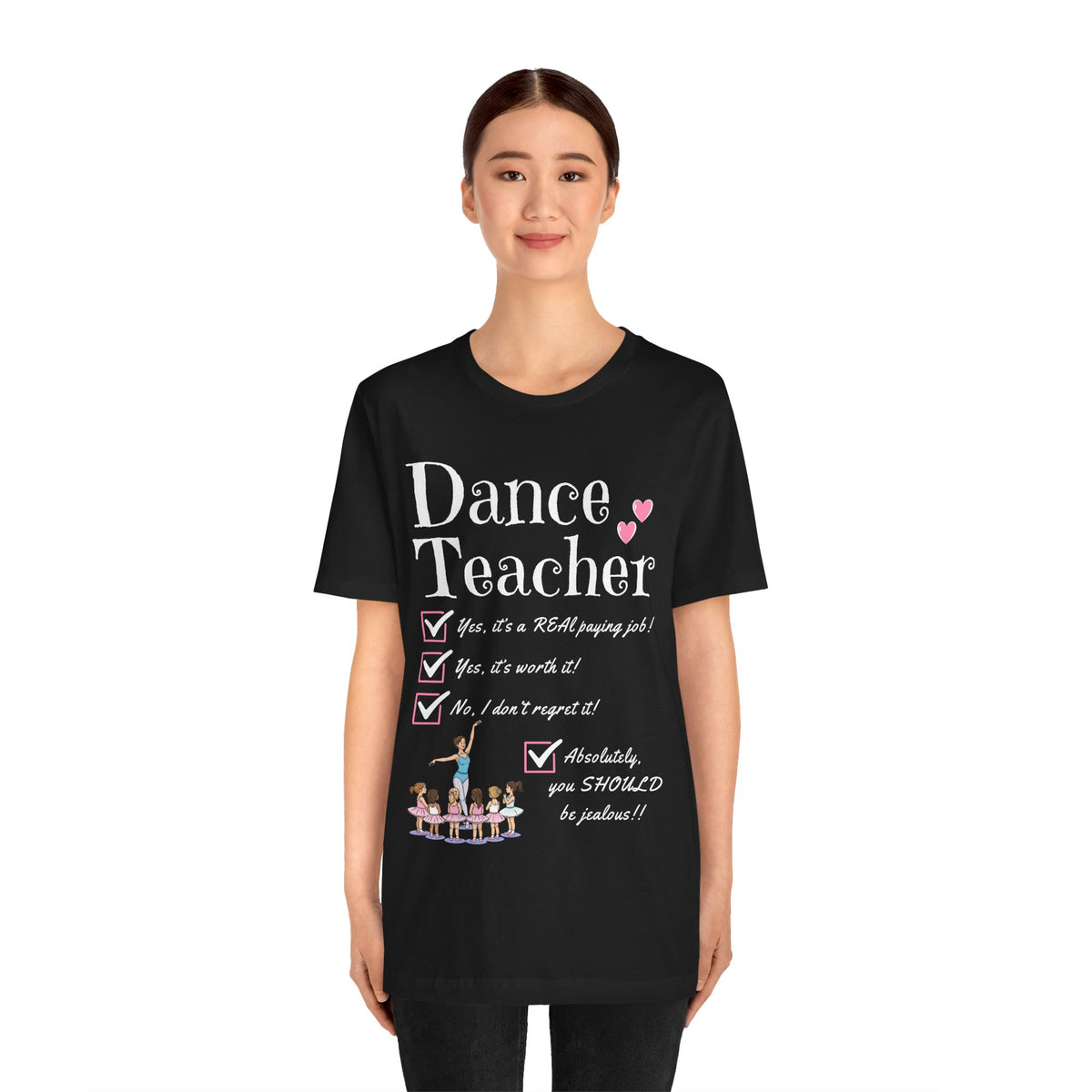 A young woman wearing a black short-sleeve crewneck t-shirt featuring a text that reads Dance Teacher and a ballet class graphic.