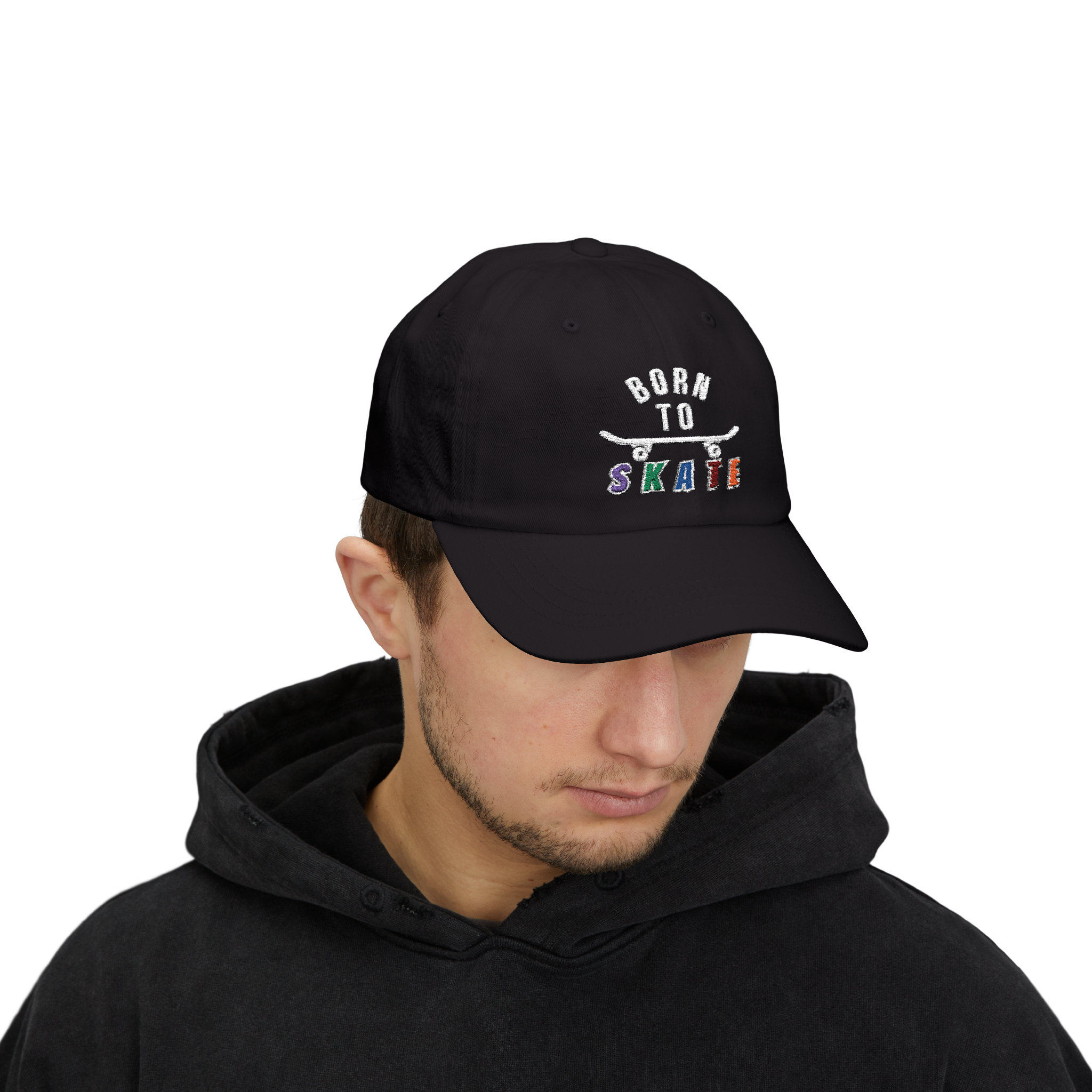 Man wearing a black baseball cap featuring a graphic on the front that reads BORN TO SKATE with a skateboard illustration. 