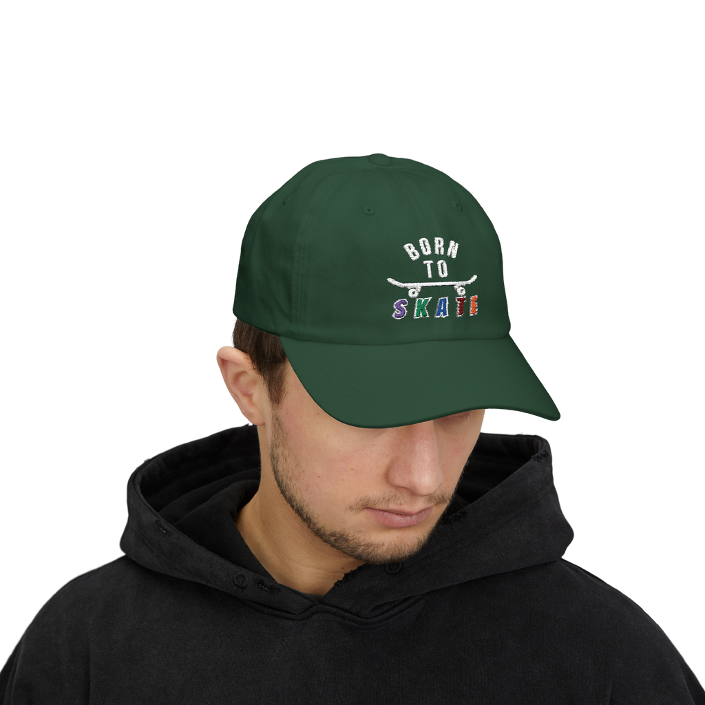 Man wearing a spruce baseball cap featuring a graphic on the front that reads BORN TO SKATE with a skateboard illustration. 