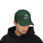 Man wearing a spruce baseball cap featuring a graphic on the front that reads BORN TO SKATE with a skateboard illustration. 
