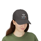 A woman wearing a dark grey baseball cap featuring a graphic on the front that reads BORN TO SKATE with a skateboard illustration. 
